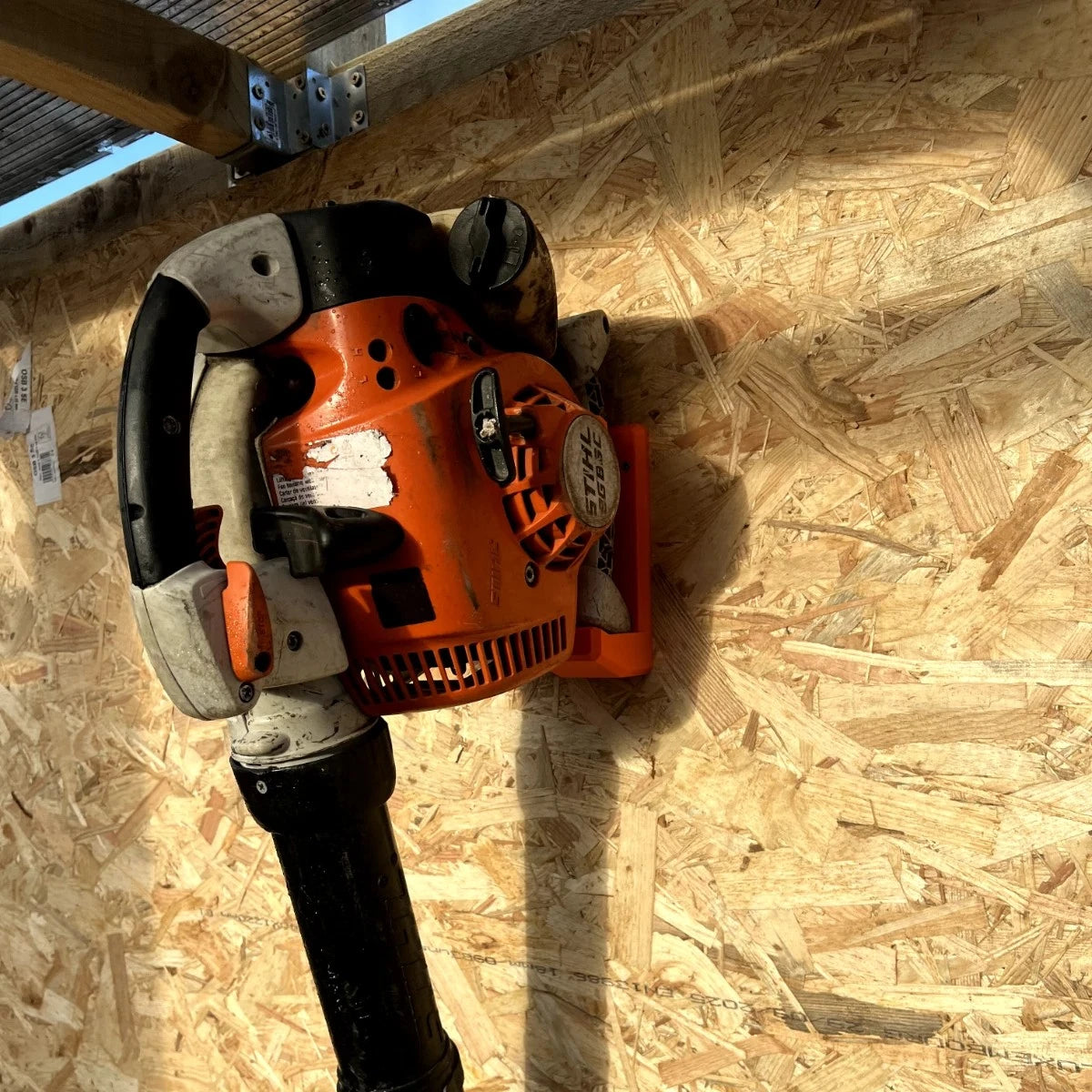 Leaf blower mounted on wall hanger